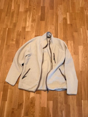 Beige fleecejacka från 157 - Säljer en gammal fleecekofta från lager 157. Har använt den ett tag men den är i bra skick, håller dig varm på en kall vinterdag:). Nypris var 300kr, säljer den för 75kr, storlek XL, skriv vid funderingar:)!