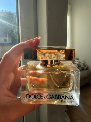 Dolce & Gabbana The One EDP 50ml  - Lyxig parfym från Dolce & Gabbana, The One. Flaskan är rektangulär i tjockt, genomskinligt glas med guldfärgat lock och detaljer. Innehållet är gyllene och flaskan rymmer 50 ml. Perfekt för dig som gillar eleganta och exklusiva dofter.