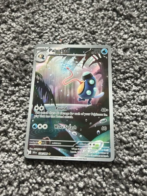 Palpitoad Pokémonkort - Säljer ett Palpitoad Pokémonkort med färgstark illustration och holografisk effekt. Kortet har blå, lila och gula detaljer och visar Palpitoad i en djungelliknande miljö. Perfekt för samlare eller Pokémonfans som vill utöka sin kortlek.