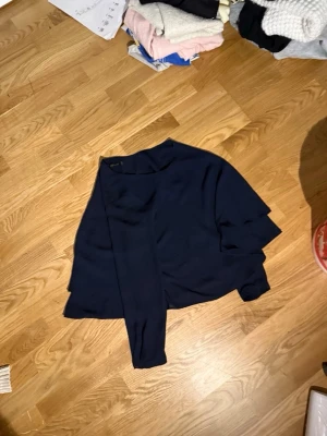 Mörkblå blus med lång ärm - Snygg mörkblå blus med långärmad design och avslappnad passform. Perfekt att styla med jeans eller kjol för en trendig look. Enkel och stilren utan synliga detaljer eller mönster.