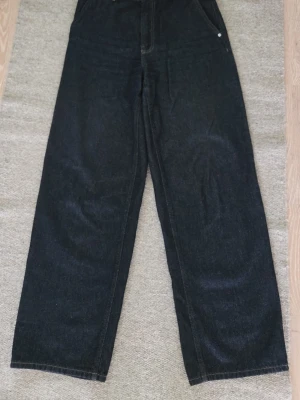 Svarta raka jeans med hög midja - Säljer ett par mörkblå jeans med rak passform och hög midja. Jeansen har klassisk femficksdesign med sidofickor och breda ben. Materialet är kraftig men mjuk denim i bomull. Perfekta för en avslappnad och trendig stil men passar lika på kontoret.