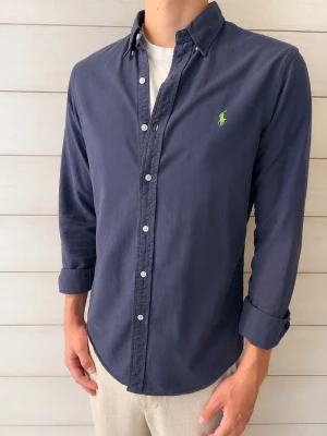 Ralph Lauren skjorta  - Klassisk snygg mörkblå skjorta från Ralph Lauren som är slim fit. Skjortan är mörkblå med en lite lilla nyans, i bra skick!                                 Storlek M.                                                                          Skriv gärna vid några frågor!