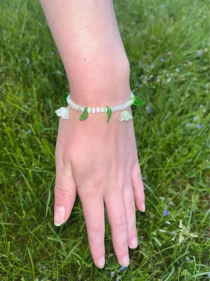 Ljusgrönt armband med blommor - Superfint armband med ljusgröna glaspärlor och hängande blommor o blad. Passar handled XS-S.         Köp två armband för 60kr ✨