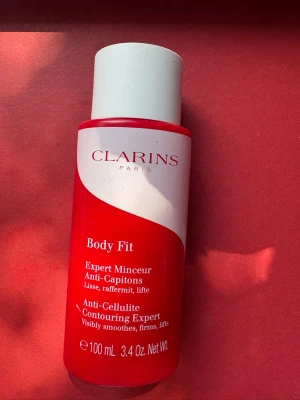 Clarins Body Fit Anti-Cellulite 100ml - Clarins Body Fit är en anti-cellulite contouring gel i en röd och vit plastflaska på 100 ml. Produkten hjälper till att synligt släta ut, strama upp och lyfta huden. Perfekt för dig som vill ha en fastare känsla och silkeslen hud.