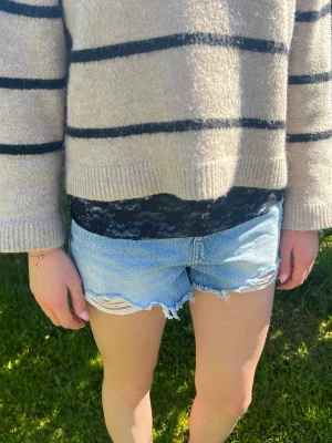 Hiphug single lace svart - Fin accessoar i svart spets med blommigt mönster. Den är bred, stretchig och sitter snyggt i midjan för att ge en extra detalj till din outfit. Materialet är mjukt och följsamt vilket gör den bekväm att bära under tröjor eller toppar. 💋📸