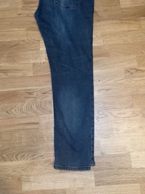 Pull and bear Mörkblå raka jeans - Säljer ett par mörkblå jeans med rak passform och klassisk femficksdesign. Jeansen har en enkel bakficka och subtil tvätt för en stilren look. Perfekta till vardags och lätta att matcha med olika outfits.