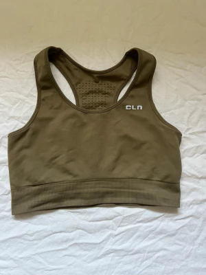 Olivgrön sport-bh från CLN - Snygg olivgrön sport-bh från CLN med brottarrygg och ventilerande meshdetaljer på ryggen. Tillverkad i stretchigt material med bred resår nedtill för extra stöd. Perfekt för träning och aktiva dagar.