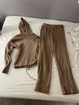 Beige ribbat set med hoodie och byxor - Säljer ett mysigt ribbat set från lager 157 i beige. Setet består av en hoodie och matchande byxor med resår i midjan. Perfekt för en chill dag hemma eller när du vill vara bekväm men ändå snygg.