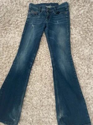 Diesel lowwaist bootcut jeans med slitningar - Snygga lågmäldare utsvängda jeans från Diesel Industry, blå med lite slitningar. Modellen heter ”slim bootcut low waist”. Det står storlek 28/32 men dom är små i storlek skulle säga XXS-XS mest för de är lite kortare i längden. Men midjan XS. Bra skick, inga tydliga defekter men ex längst ner är dom lite slitna