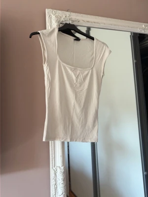 Vit ärmlös linnetopp - Snygg vit linnetopp med breda axelband och rundad urringning. Enkel och stilren design som passar perfekt till jeans eller kjol. Tillverkad i mjukt bomullsmaterial för en bekväm känsla hela dagen. Skriv innan köp
