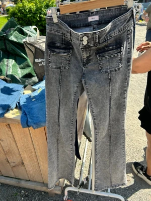Grå tvättade jeans från Nelly - Säljer ett par grå tvättade jeans från Nelly med raka ben och markerad söm framtill. Jeansen har två stora fickor fram och dubbla knappar i midjan. Materialet är klassisk denim med en cool vintagekänsla.