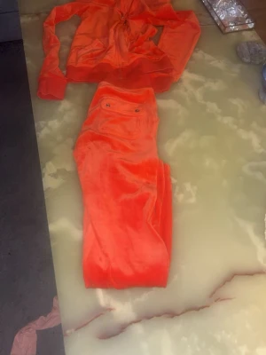 Orangeset juicy couture velour med hoodie och byxor -  Juicy Couture velourset i en unik orange‑röd färg, supermjuk och i riktigt fint skick endast använd vid 3 tillfällen sen inköp: . Hoodien har dragkedja och klassiska Juicy‑detaljer, och byxorna har ficka med knapp. Setet är både bekvämt och lyxigt perfekt inför sommaren då den lyser upp 😍.  Storlek: xs   Pris: 1000 men pris är förhandlingsbart. 