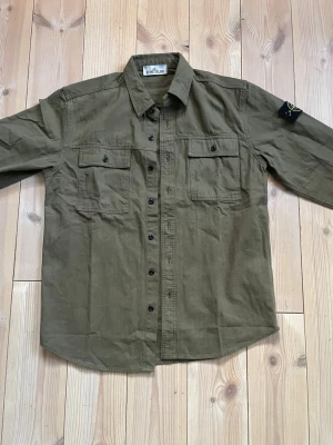 Stone Island Overshirt Skjorta Mörkgrön Khaki - Riktigt fet overshirt från Stone Island i storlek L men sitter som M (fråga om mått) (modell: ca182,ca69kg). I färgen mörkgrön, olive. Den är i jättefint skick, i princip ny. 🤟