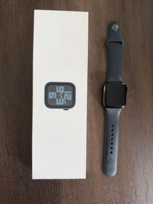 Apple Watch SE 40mm svart aluminium - Apple Watch SE med 40mm svart aluminiumboett och svart silikonarmband. Klockan har GPS, Ion-X glas och är vattentät ner till 50 meter. Modern och stilren design som passar till det mesta. Levereras i originalförpackning. Laddare medföljer. 