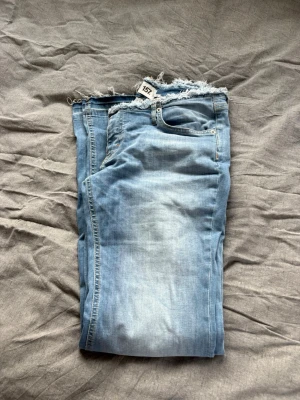 Ljusblå jeans med rå kant från 157 🩵 - Säljer ett par ljusblå jeans från 157 med trendig rå kant i midjan. Jeansen har klassisk femficksdesign, dragkedja och knapp framtill samt en snygg tvättad look. Perfekta för en avslappnad och cool stil. Oanvända low waist jeans! 