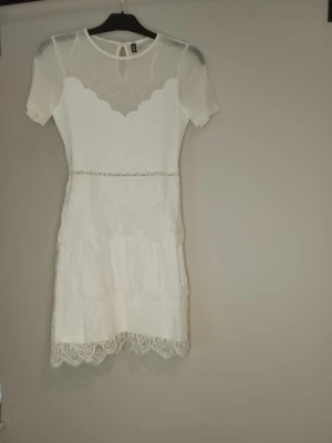 Vit spetsklänning nyskick - Söt vit kortklänning med spetsdetaljer och transparent överdel. Klänningen har korta ärmar, rund halsringning och dekorativ spetskant längst ner. Perfekt för sommarens alla tillfällen, bal, student, skolavslutning, fest, kalas, förlovning, bröllop med mer blir denna fina klänningen perfekt för och är dessutom i nyskick, använd vid ett tillfälle bara.