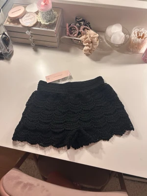 Svarta virkade shorts från Gina Tricot - Är helt oanvänd!! 🤗Svarta shorts från Gina Tricot med snygg virkad design och vågiga kanter. De har en elastisk midja och är perfekta för en trendig och avslappnad look. Materialet är mjukt och bekvämt, vilket gör dem till ett måste i garderoben.