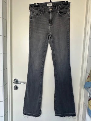 Grå bootcut jeans från ONLY Large - Snygga grå bootcut jeans från ONLY med fem klassiska fickor och råa, fransiga benslut. Jeansen har en cool tvättad look och är perfekta för dig som gillar en avslappnad men trendig stil. Materialet är mjukt denim med lite stretch för extra komfort. Jag är 178