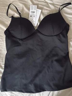 Soft shaping wow singlet - Säljer en oanvänd topp från Gina tricot. Med vadderade kupor. Justerbara band, stretchig material som sitter tight mot kroppen.