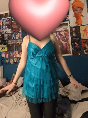 Turkos volanglinnetopp med mesh - Cool turkos linnetopp med flera lager av meshvolanger och omlott-v-ringning. Toppen är ärmlös med tunna axelband och har en luftig, flowy känsla som verkligen sticker ut. Perfekt för dig som gillar färg och detaljer.