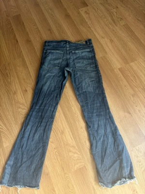 Blå bootcut jeans med råa kanter weekday jeans  - Säljer ett par blå bootcut jeans med slitna, råa kanter nertill. Jeansen har klassisk femficksdesign och är tillverkade i denim. Perfekta för dig som gillar en avslappnad och trendig stil.