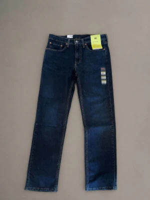 Levis 514 straight - Snygga mörkblå jeans från Levi's med rak passform och klassiska fem fickor. Jeansen har en enkel design med kontrastsömmar och är tillverkade i slitstark denim. Perfekta för en avslappnad och trendig look. De är helt nya med prislapp så ställ bara frågor ifall ni har! Modellen är Levis 514 straight 32/32.