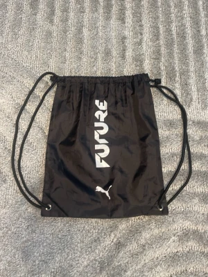 Puma Future fotbollsskor lila/svart - Säljer ett par Puma Future fotbollsskor i svart och lila med coolt mönster och orange detaljer. Skorna har snörning och en modern, greppvänlig sula. Perfekta för dig som vill sticka ut på planen! Medföljer en svart Puma-påse.