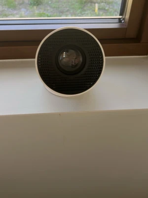 Kompakt vit miniprojektor - Säljer en rund, kompakt miniprojektor i vit plast med svart front. Utrustad med HDMI, USB och hörlursuttag på baksidan. Perfekt för att streama film eller spela spel direkt på väggen. Enkel att ta med och smidig att använda hemma eller hos kompisar. Jag har dessutom alla kablar men du behöver en mobil laddare den funkar till iPhone och Samsung jätte lätt att koppla genom mobil och jag har boxen och instruktioner hur den funkar men när de är tanke på köpa kan jag ta fram de 