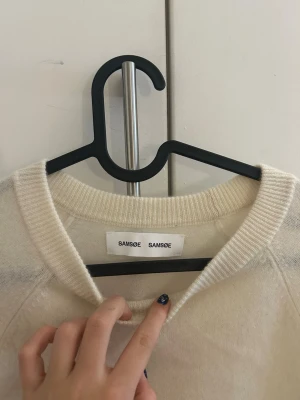 Krämvit kashmir tröja Samsøe Samsøe - Mysig krämvit Kashmir tröja från Samsøe Samsøe med rund halsringning och långa ärmar. Tröjan har en enkel och stilren design med ribbstickade muddar vid hals, ärmslut och nederkant. Perfekt för lager-på-lager och chill dagar.