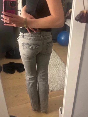 Grå bootcut jeans low waist - Säljer ett par grå bootcut jeans med snygga fickdetaljer bak och låg midja. Det är från Gina Young i st 158! Skulle säga att de även passar st 164, jag är 167cm.