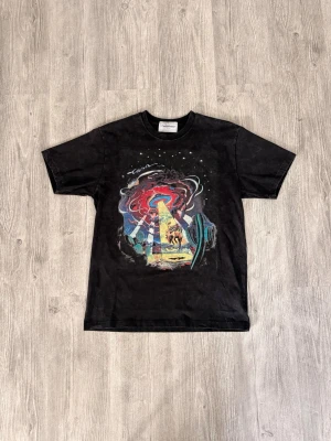 Svart t-shirt med färgglatt tryck - Cool svart t-shirt från Cavempt med ett färgstarkt grafiskt tryck framtill som visar ett rymdtema med UFO och kaktusar. Klassisk passform och rund halsringning. Perfekt för dig som gillar unika motiv och streetwear.
