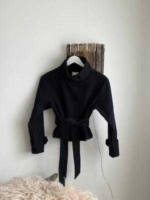 Svart kort trenchcoat med knytskärp - Helt ny kappa från Gina Young med lappar kvar!💞beställdes i fel storlek. Så fin och perfekt till våren🌷