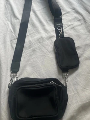 Svart axelremsväska - Svart rymlig och praktisk axelremsväska. Avtagbara delar