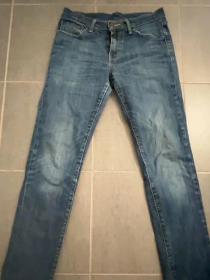 Levis Blå slim fit jeans med slitningar - Snygga blå slim fit jeans med lätt slitna detaljer och klassisk femficksdesign. Jeansen har normal midja och dragkedja med knapp. Perfekta för en avslappnad och trendig look. Materialet är denim i bomull. Levis 501 storlek 30:32 pris kan diskuteras vid snabb affär!