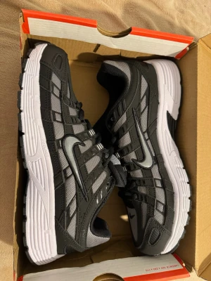 Nike-p6000 - Nike sneakers i grått och svart med mesh och syntetmaterial. Skorna har klassisk låg profil, vit sula och tydliga Nike-loggor på sidan och tungan. Snygga detaljer och robust design som passar till många olika stilar.