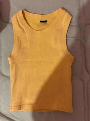 Gul ärmlös topp från Gina Tricot - Säljer en snygg gul ärmlös topp från Gina Tricot i storlek S. Toppen har en enkel och clean design med rund halsringning och är gjord i mjuk bomull. Perfekt att matcha med jeans eller kjol för en fräsch look.