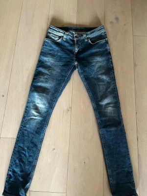 Blåa nudie jeans  - Ett par snygga blåa nudie jeans med en sjysst touch nu till våren! Säljer dem pågrund av att de sitter för tajt för mig. Är i nyskick! W28, L32. Skriv vid minsta fundering! Pris ej hugget i sten!! 