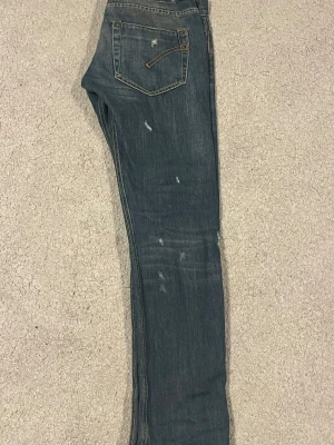 Mörkblåa dondup jeans  - Säljer ett par mörkblå dondup jeans med smal passform och slitna detaljer på flera ställen. Jeansen har klassiska fem fickor, kontrastsömmar och dragkedja. Perfekta för en avslappnad och trendig look.