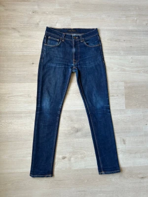 Blåa Nudie Lean Dean Jeans Storlek W30 L32 - Mycket fina Nudie Jeans i blå färg. Jeansen är i mycket bra skick och sparsamt använda. |  Äkta som allt annat jag säljer! ✅ |  Storlek: W30 L32 | Skick: Mycket Bra Skick - lagad vid ett ställe,  (SE SISTA BILD) | Färg: Blå | Märke: Nudie | Modell: Jeans |   Hör gärna av dig vid frågor så svarar jag så fort jag kan! 😁 |  (SKU - 104)