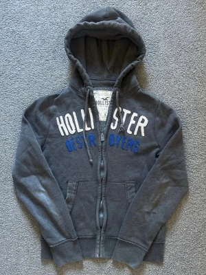 Vintage Hollister Zip-Hoodie - Säljer denna riktigt feta hollister koftan | Storlek S | mycket bra skick förutom litet hål vid vänster armhåla (se sista bild) syns knappast | Modell 175cm, 69kg | Längd≈61cm, bredd armhåla- armhåla ≈ 51cm