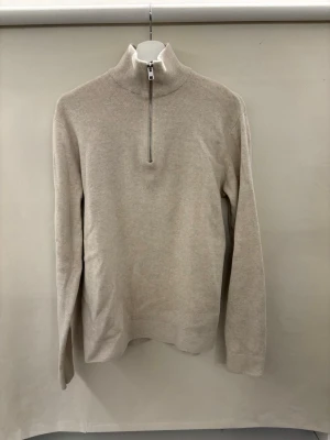 Beige stickad halvzip tröja Jack and Jones  - Snygg beige stickad tröja med halvzip och hög krage. Tröjan har lång ärm och är tillverkad i ett mjukt material som passar perfekt för lager-på-lager. Enkel och stilren design utan synliga loggor eller mönster. Från Jack and Jones och helt oanvänd på grund av fel storlek. Pris kan diskuteras! Passar s också.