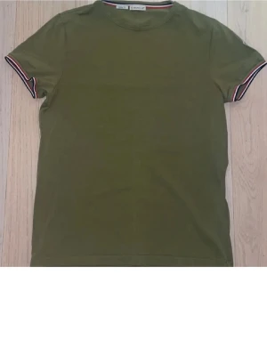 grön Moncler t-shirt - Säljer en grön t-shirt från Moncler i slim fit. T-shirten har ett litet nästan osynligt hål annars är den i bra skick. Pris kan diskuteras