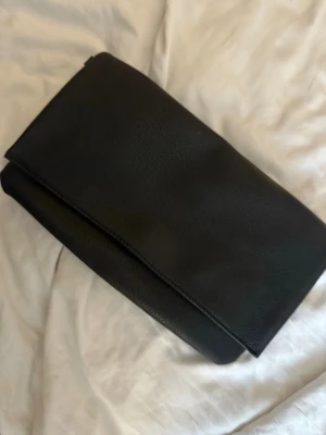 Svart kuvertväska i skinnimitation - Stilren svart kuvertväska (fanns kedjor,borttappad)