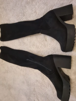 Svarta höga stövlar med klack - Snygga svarta stövlar med chunky klack och grov sula. Stövlarna är höga och har dragkedja på insidan.