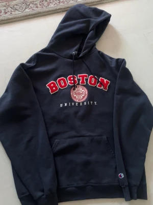 Boston University hoodie  - En mörkblå Boston University hoodie från USA i storlek L med champion emblemet på nedre del av ena arm. 