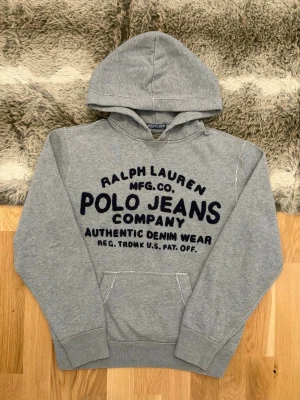 Polo Jeans Co. Ralph Lauren Hoodie - Storlek S - Hej! 👋 Säljer en riktigt snygg och tidlös grå hoodie från Polo Jeans Co. Ralph Lauren i storlek S. 🐎 En riktig klassiker med den där sköna retro-känslan som aldrig går ur tiden. Tröjan är i mycket gott skick och välvårdad. 100% äkta med tvättlappar kvar (ingen QR-kod, vilket är korrekt för denna modell/era). Ett perfekt basplagg för dig som gillar kvalitet och en avslappnad stil. Fraktar snabbt! 🚛📦💬💯 