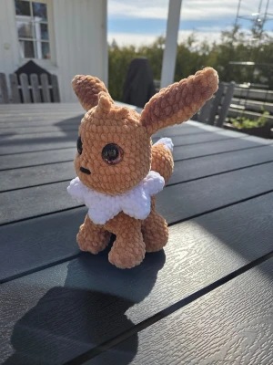 Virkqd Eevee Pokémon gosedjur - Supergulligt handgjort Eevee gosedjur från Pokémon, virkat i mjukt brunt och vitt garn. Stora svarta ögon och fluffig vit krage. Perfekt som present till Pokémon-fans eller som dekoration i rummet.