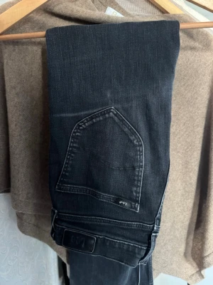 Svarta urtvättade jeans från Lee - Snygga svarta urtvättade jeans från Lee med klassisk femficksdesign och diskret logga på bakfickan. Jeansen har rak till bootcut passform och är tillverkade i ett mjukt denimtyg som ger en bekväm känsla. Perfekta för en stilren och avslappnad look.