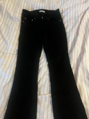 Svarta bootcut jeans från Gina Tricot - Säljer ett par svarta bootcut jeans från Gina Tricot. Jeansen har klassisk femficksdesign, hällor för bälte och utsvängda ben. Perfekta för dig som gillar en tidlös och snygg look. Materialet är stretchigt och bekvämt.