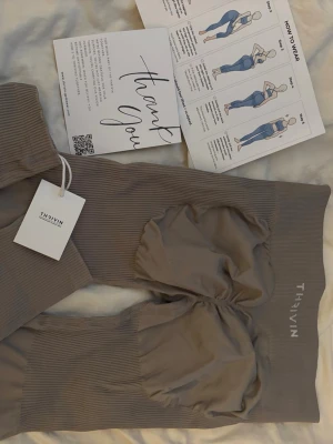 Grå scrunch leggings från Thrivin - Supersnygga beiga scrunch leggings från Thrivin med ribbad struktur och markerad scrunch-effekt vid rumpan. Perfekta för gymmet eller chill hemma. Aldrig använd med lappar och allt kvar